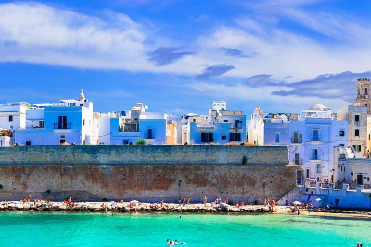 Gruppo di escursionisti in cammino sulla costa tra Monopoli e Capitolo, vista mare, cielo limpido, atmosfera rilassata